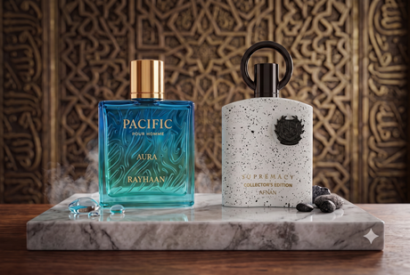 A high-end close-up product photograph featuring two luxury Arabian perfume bottles from Rayhaan and Afnan, elegantly displayed on a bed of smooth dark pebbles with glistening water droplets.